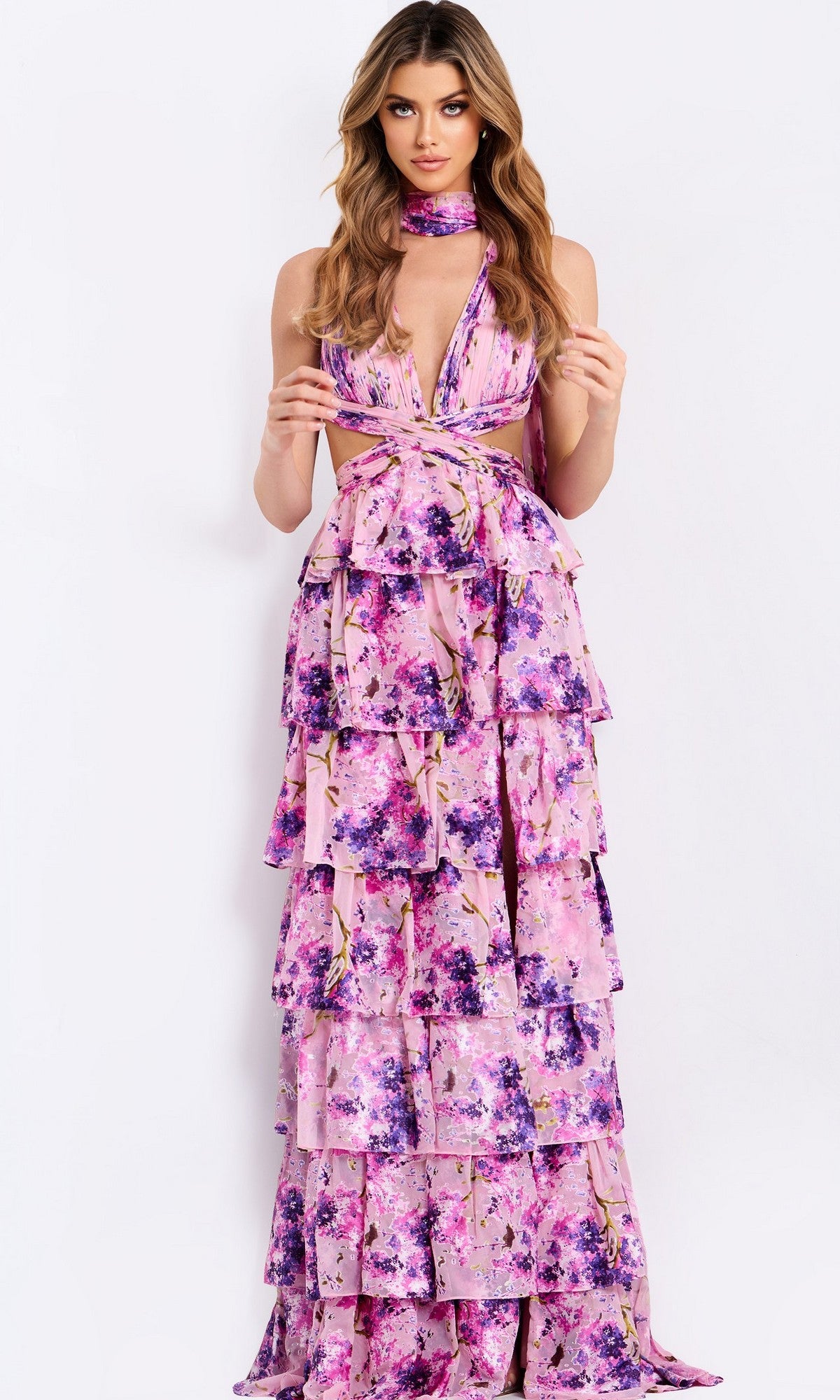 Woman wearing Jovani 48234, a long prom dress with sleeveless design, pink and purple floral tiered ruffles, plunging neckline, and matching neck scarf, standing against a plain white background.